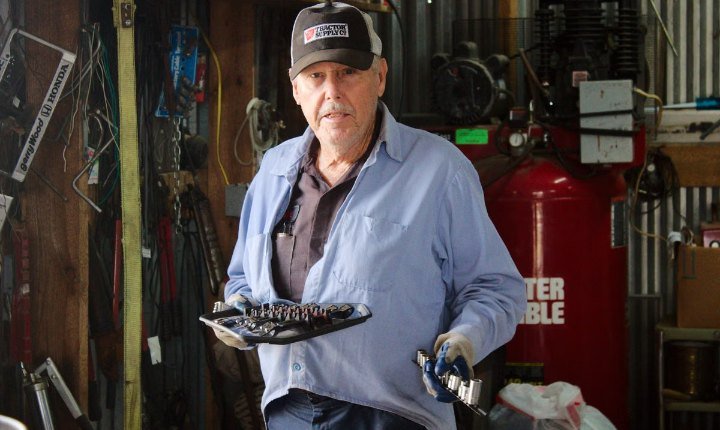 Mechanic in his own workshop holding tools