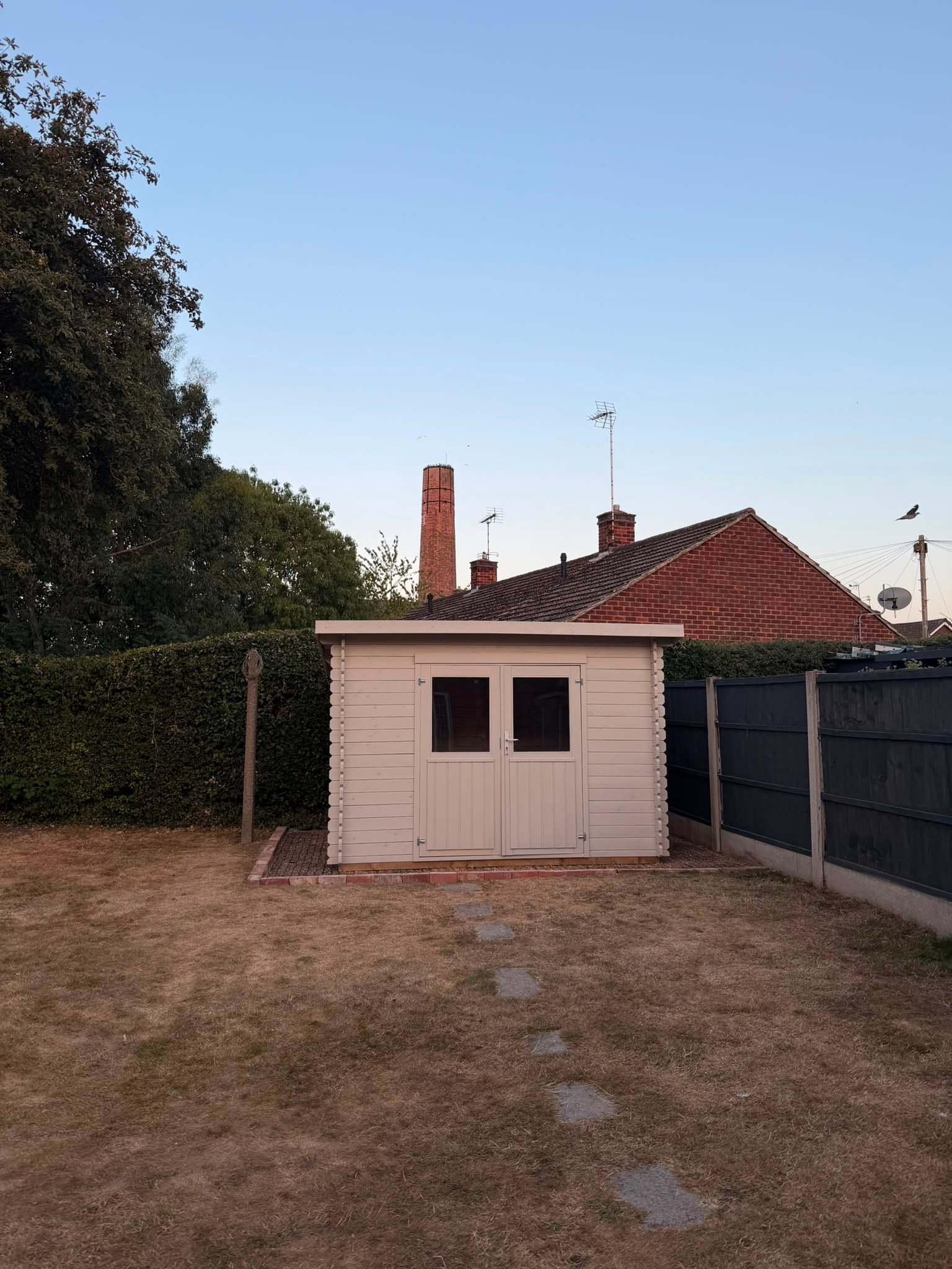 A newly installed garden building in a back garden at dusk, photographed front on.