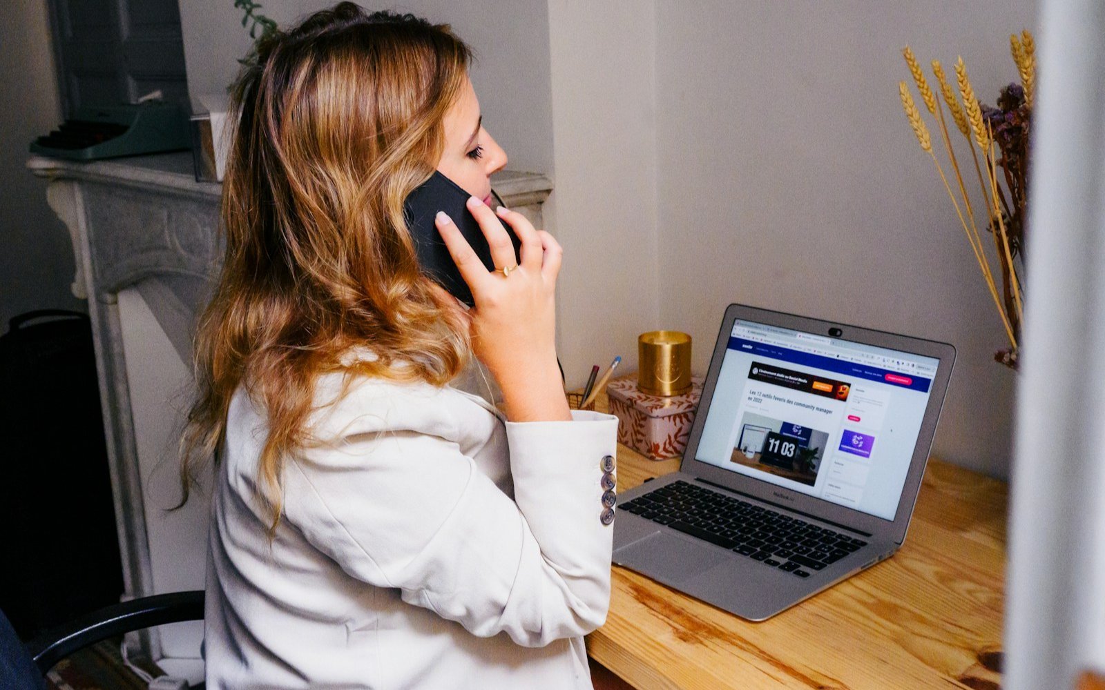 A woman at a desk with a laptop taking a phone call