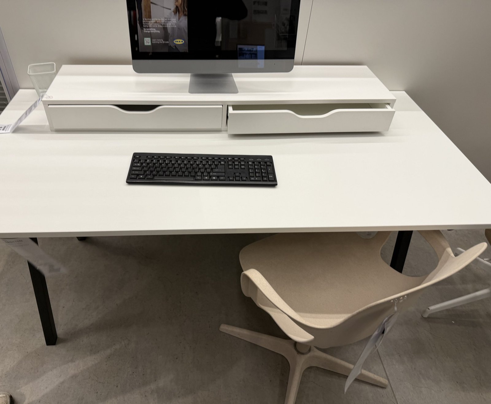 A tidy white desk with a monitor and keyboard, empty and ready to work at.