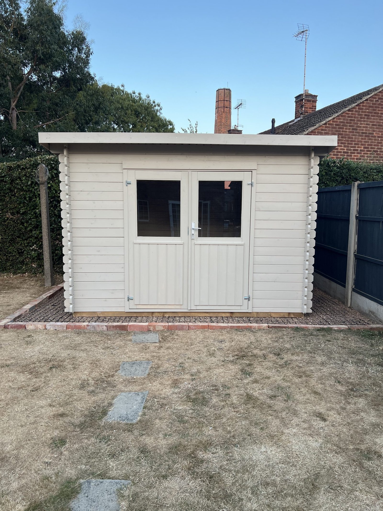 A finished garden building in a back garden on a clear day, photographed front on.