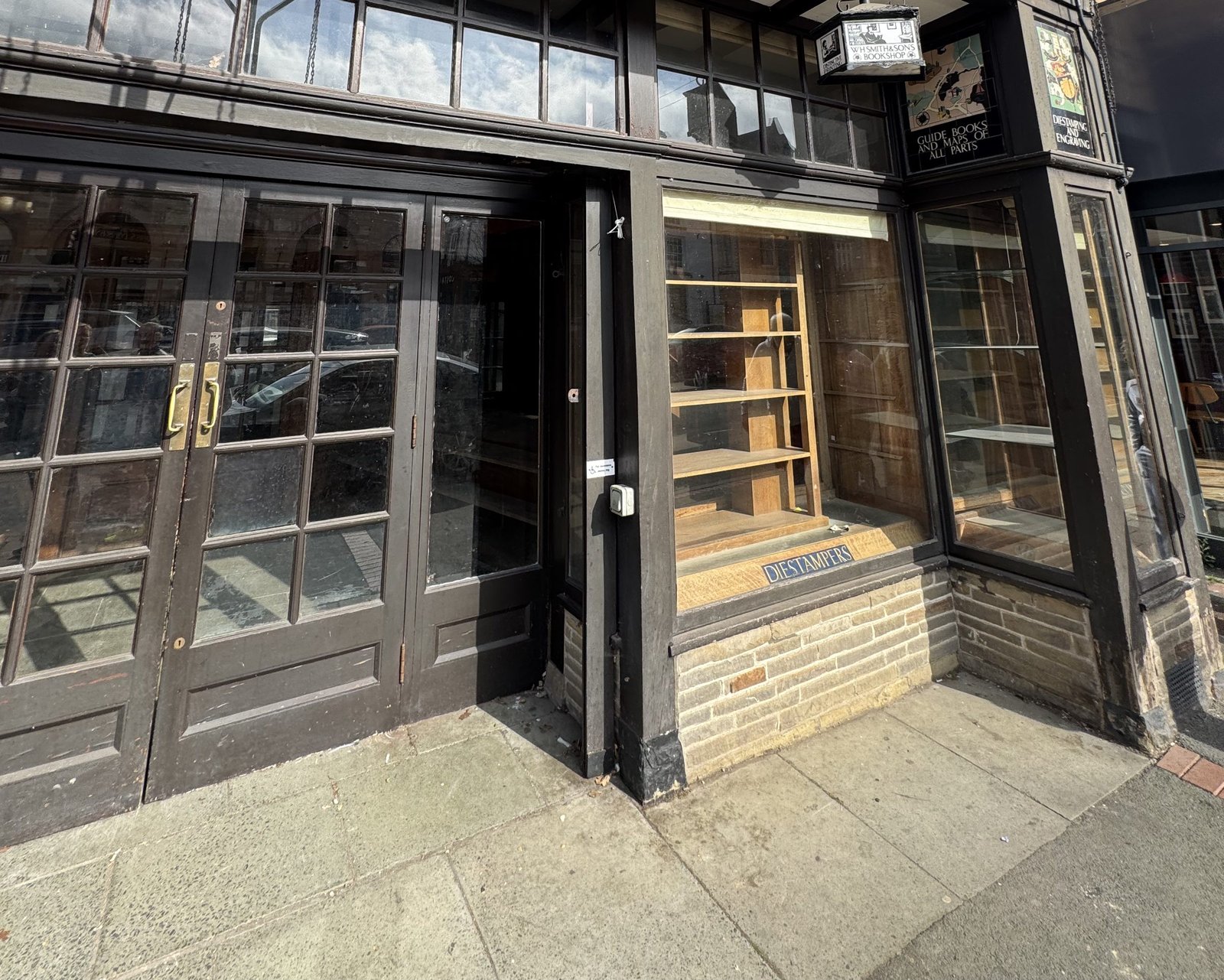 A traditional British timber shopfront with large glazed windows and a brick stall riser.