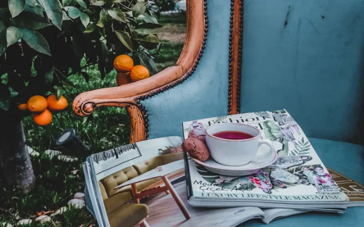 A cup of tea on magazines on an armchair