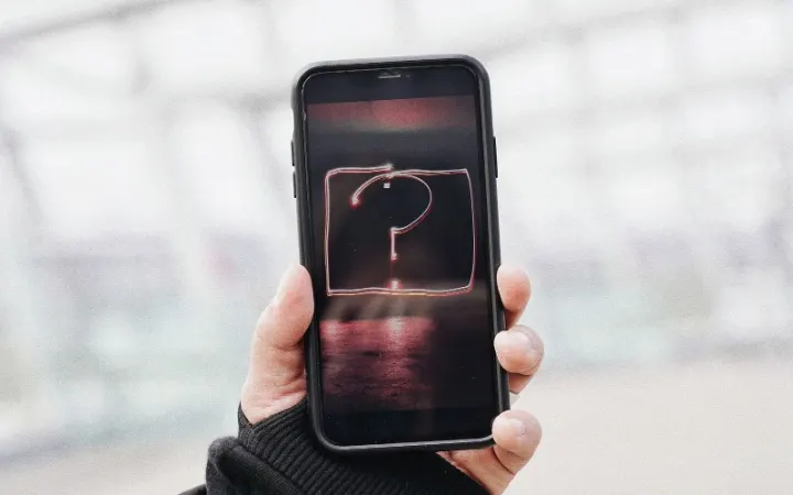 A hand holding a phone showing a question mark
